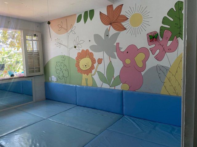 Berçário com tatame azul e parede ilustrada