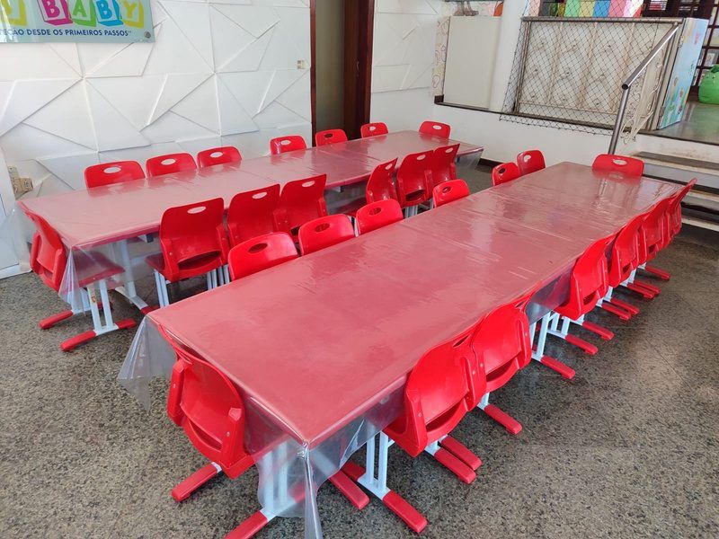 Refeitório com mesas e cadeiras vermelhas