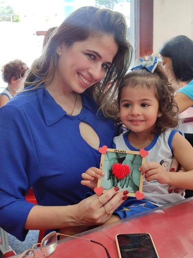 Professora e aluna com um trabalho feito em sala