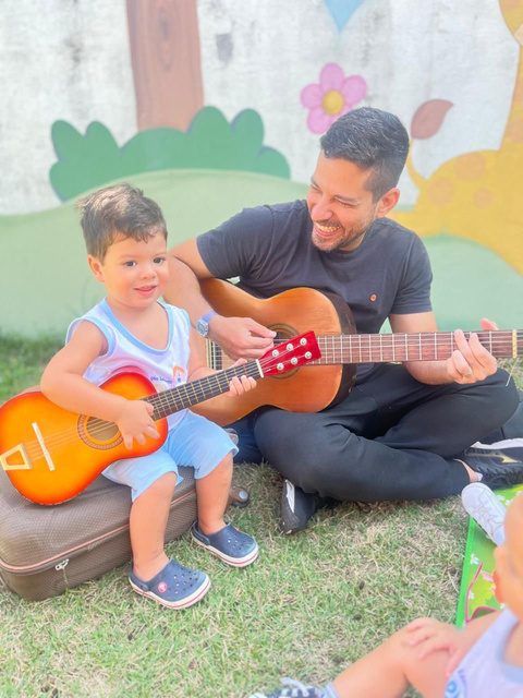 Professor tocando violão com um aluno